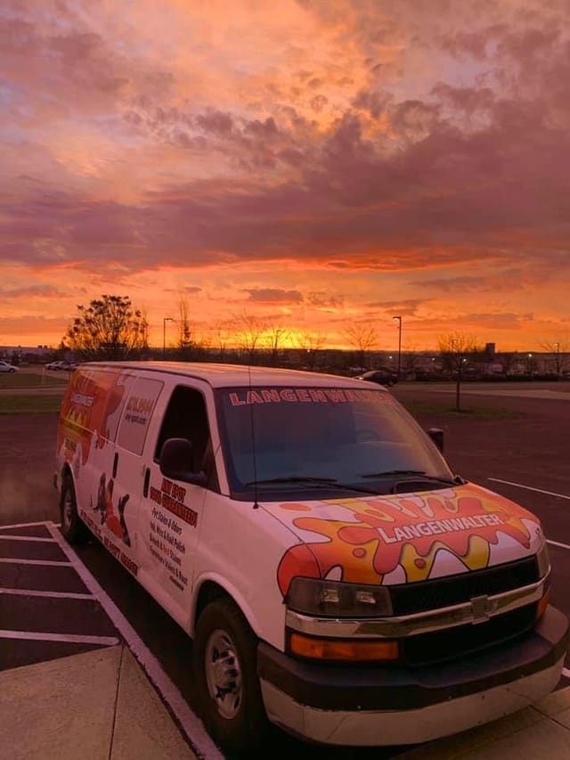 A Langenwalter van parked under a pink and orange sunset sky